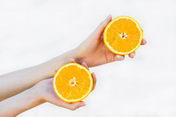 women's hands hold a juicy half orange isolated on white background. Nutrition concept, health, charge of vitamins.
