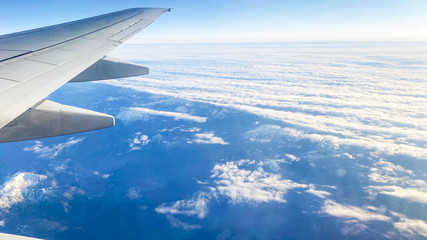 Obraz premium The view from the plane on the landscape from the window of the plane. Airplane wing flying above the clouds