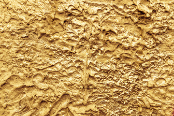 Abstract gold color painted on grunge rough surface of stucco concrete wall. Good for  texture background and wallpaper