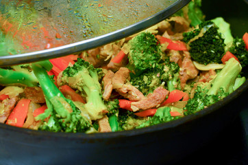 cooking meat with vegetables in a pan