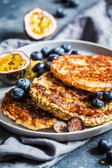 Oatmeal pancakes with honey, fruits and berries, blue background. Healthy vegan food concept.
