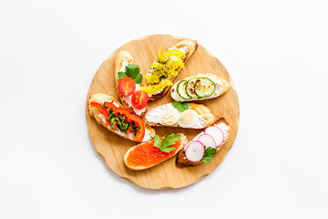 Set of bruschetta on cutting board on white background top-down copy space