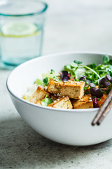 Fried tofu salad with sprouts and sesame seeds in white bowl. Vegan food, asian food concept.