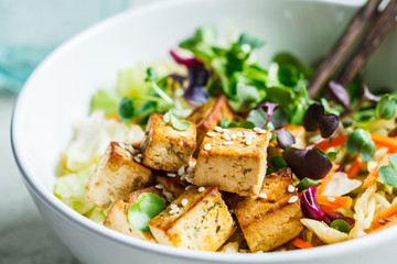 Fried tofu salad with sprouts and sesame seeds in white bowl. Vegan food, asian food concept. - obrazy, fototapety, plakaty