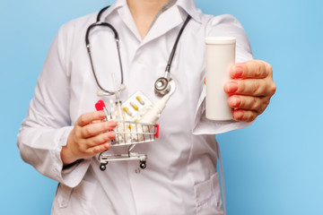 one doctor hand holds out pills close-up, and the other holds a shopping trolley with pills