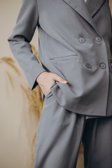 Portrait of an attractive blonde woman poses for the advertisement of a women's clothing store dressed in a gray jacket and pants with a blouse