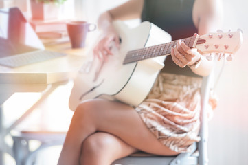Young woman playing acoustic guitar at home.