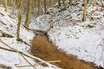 City Sigulda, Latvia. Small river with sand rock and snow in winter.Travel photo.