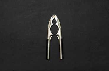 Tool for chopping nuts, nutcracker on a black background. Copy space. Flat lay. Top view.