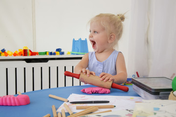 Toddler girl playing with modelling clay. Play dough allows kids to develop fine motor skills, strengthen fingers, hands and wrists and to be naturally curious and explore the world using their senses