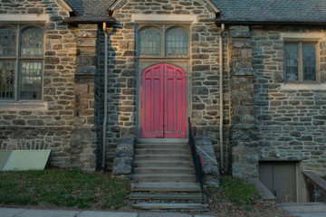 A Faded Red Door on an Old Cobblestone Church