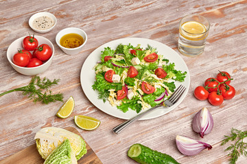Fresh salad with cherry tomatoes, savoy cabbage, cucumeber on dish. Healthy summer salad vegetarian meal concept. Tasty mixed leaves, tomatoes and mix vegetable salad on wood background