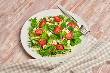 Fresh salad with cherry tomatoes, savoy cabbage, cucumeber on dish. Healthy summer salad vegetarian meal concept. Tasty mixed leaves, tomatoes and mix vegetable salad on wood background