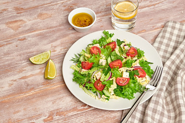 Fresh salad with cherry tomatoes, savoy cabbage, cucumeber on dish. Healthy summer salad vegetarian meal concept. Tasty mixed leaves, tomatoes and mix vegetable salad on wood background
