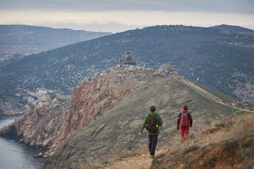 Fototapeta premium Trekkers are finishing their mountain rout and getting closer to a rocky scenic suburbs of the city.
