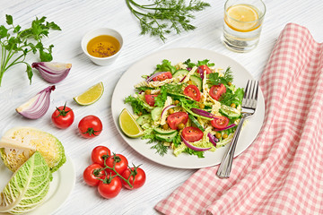 Fresh salad with cherry tomatoes, savoy cabbage, cucumeber on dish. Healthy summer salad vegetarian meal concept. Tasty mixed leaves, tomatoes and mix vegetable salad on white wood