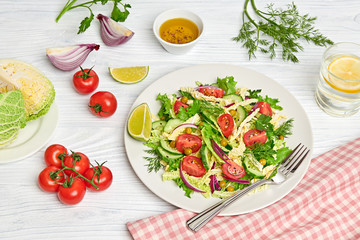 Fresh salad with cherry tomatoes, savoy cabbage, cucumeber on dish. Healthy summer salad vegetarian meal concept. Tasty mixed leaves, tomatoes and mix vegetable salad on white wood
