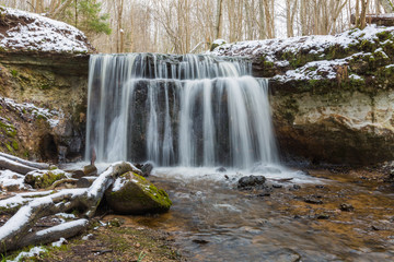 City Sigulda, Latvia. Waterfall in winter. White snow and trees. Travel photo.