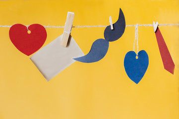 Handmade retro mustache hanging and funny paper mustache with tie over yellow background