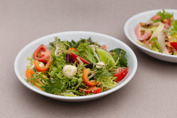 white deep plates with fresh salad ingredients mixed with sauce placed on an attractive background. A place for a menu, banner or advertisement