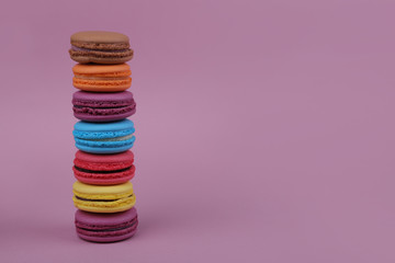  colored french macaroons on top of each otheron a pink background