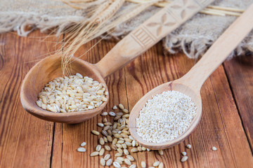 Two different barley groats in wooden spoons close-up