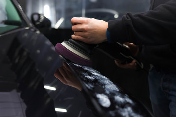Worker polishes a car’s paintwork with a car