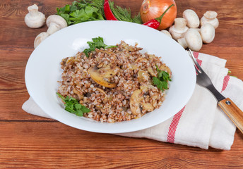 Buckwheat porridge with fried mushrooms on dish against the ingredients