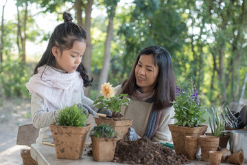 planting flowers. cute child girl helping her mother to care for plants. mom and her daughter...