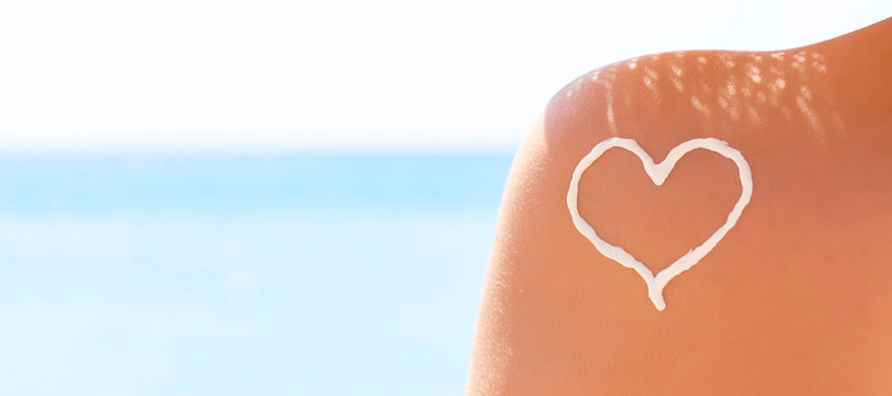 Heart made of sun cream is drawn on woman's shoulder at the beach