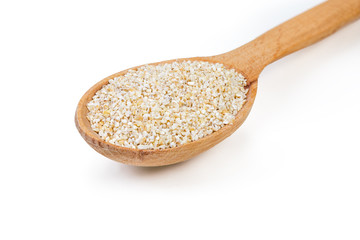 Raw barley groats in wooden spoon on a white background