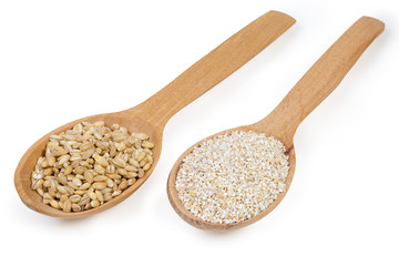 Two different barley groats in wooden spoons on white background