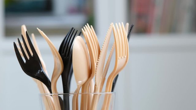 Plastic forks, knifes and spoons in glass. Concept of Recycling plastic and ecology problem