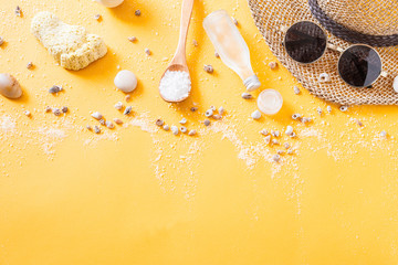 Summer traveling to the sea with straw hat, sun glasses, body oil, shells and sea salt on yellow background top view mock up. copy space