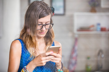 Young adult woman using smartphone in a modern home.