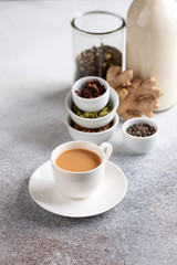 Cup of traditional indian masala chai. Ingredients for spicy milk tea on concrete background.