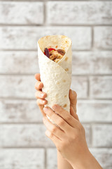 Female hands with tasty doner kebab on brick background