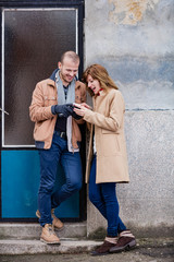 Obraz na płótnie Canvas Modern urban couple posing on the street and using smartphone.