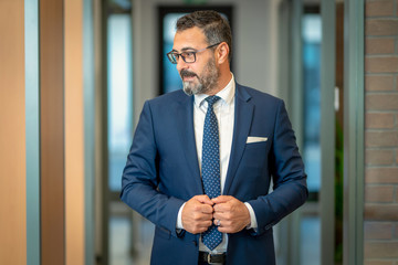 A charismatic, bespectacled banker is strong and happily ready for the meeting in his stylish suit