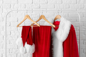 Hanger with Santa Claus costume near brick wall