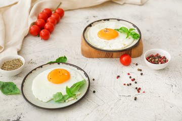 Plates with fried eggs on white background
