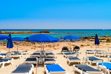 blue sunbeds and umbrellas on the famous cyprus beach nissi beach