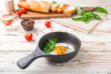 Frying pan with cooked egg on white wooden background
