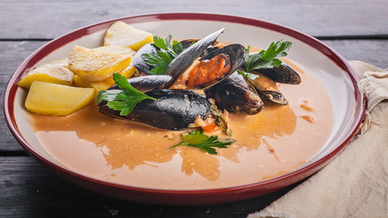 Food banner. Mussels and fried potatoes in sweet and sour sauce on a dark wooden table.