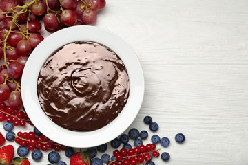 Bowl with tasty chocolate fondue and berries on white table