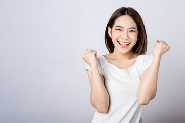 Asian pretty woman in white t-shirt and white pants pretending glad happy face with copy space on white background. Information telling, shopping promotion, announcement, selling support concept.