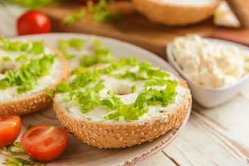 Fresh bun with tasty cream cheese and vegetables on plate