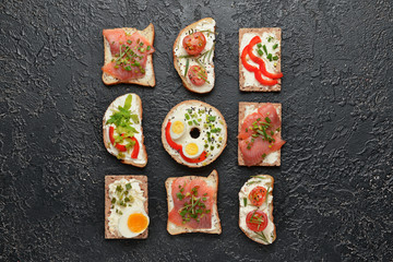 Different sandwiches with tasty cream cheese on dark background