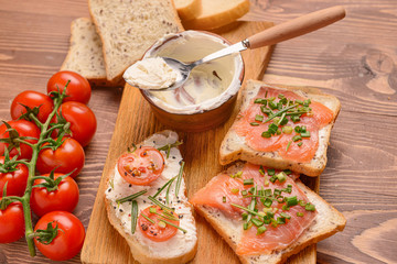 Sandwiches with tasty cream cheese, salmon and tomatoes on table