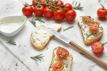 Fresh bread with tasty cream cheese and tomatoes on white background